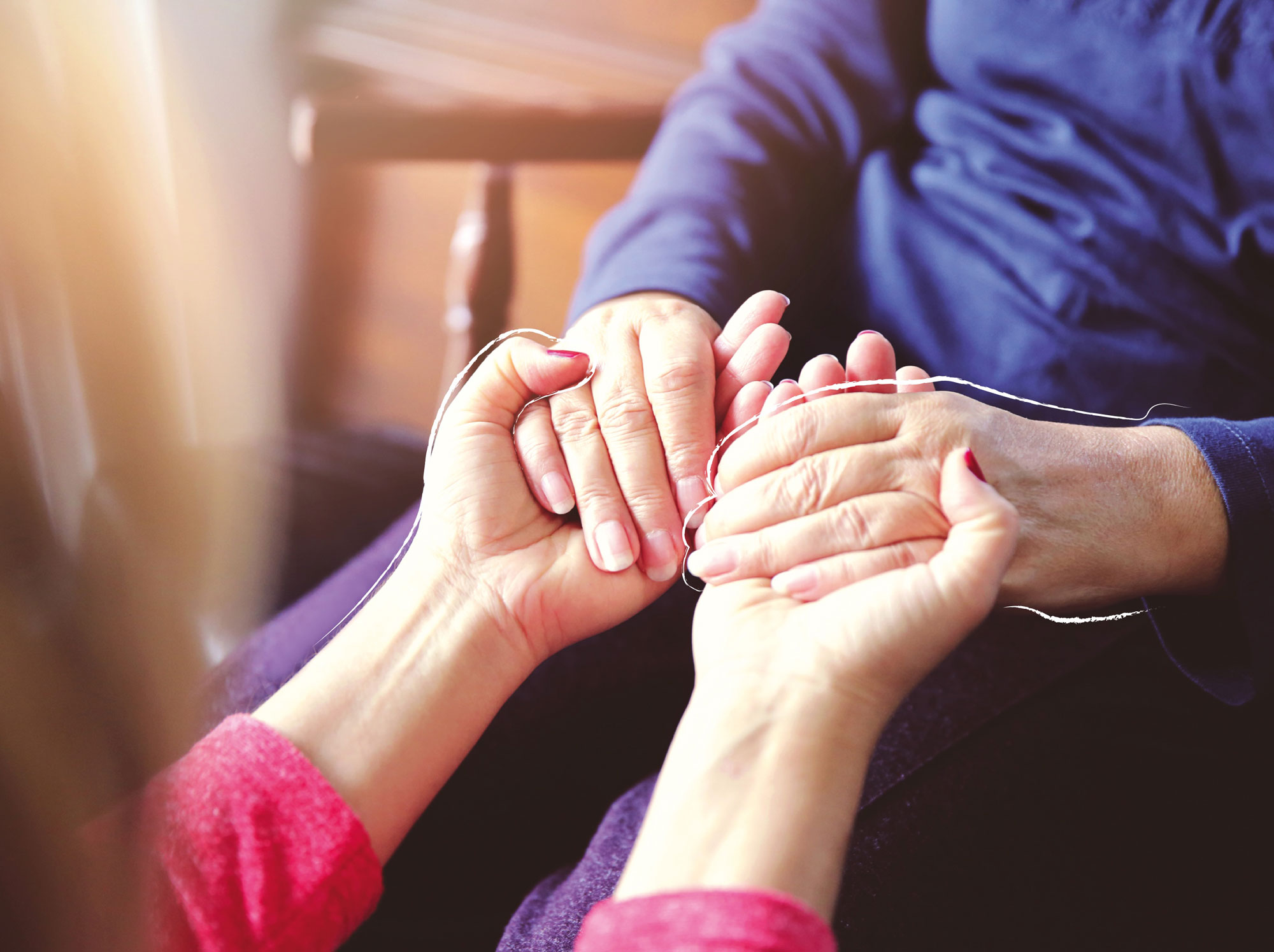 Zwei junge Hände halten zwei ältere Hände