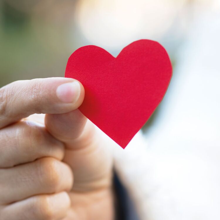 Eine Hand hält ein rotes Papierherz.