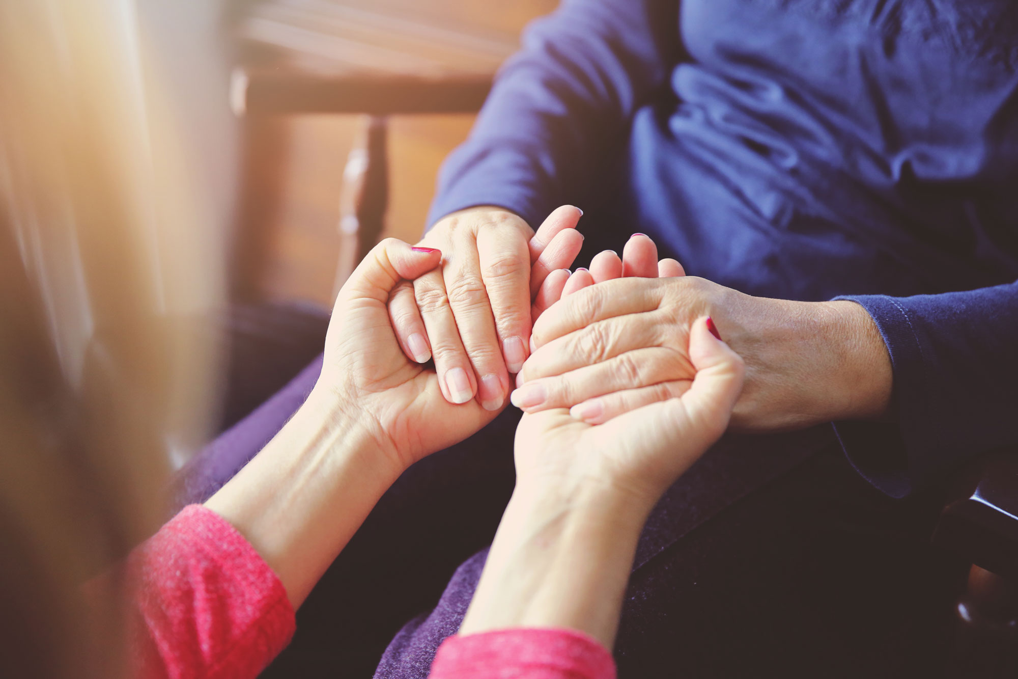Zwei Personen reichen sich tröstend ihre Hände.