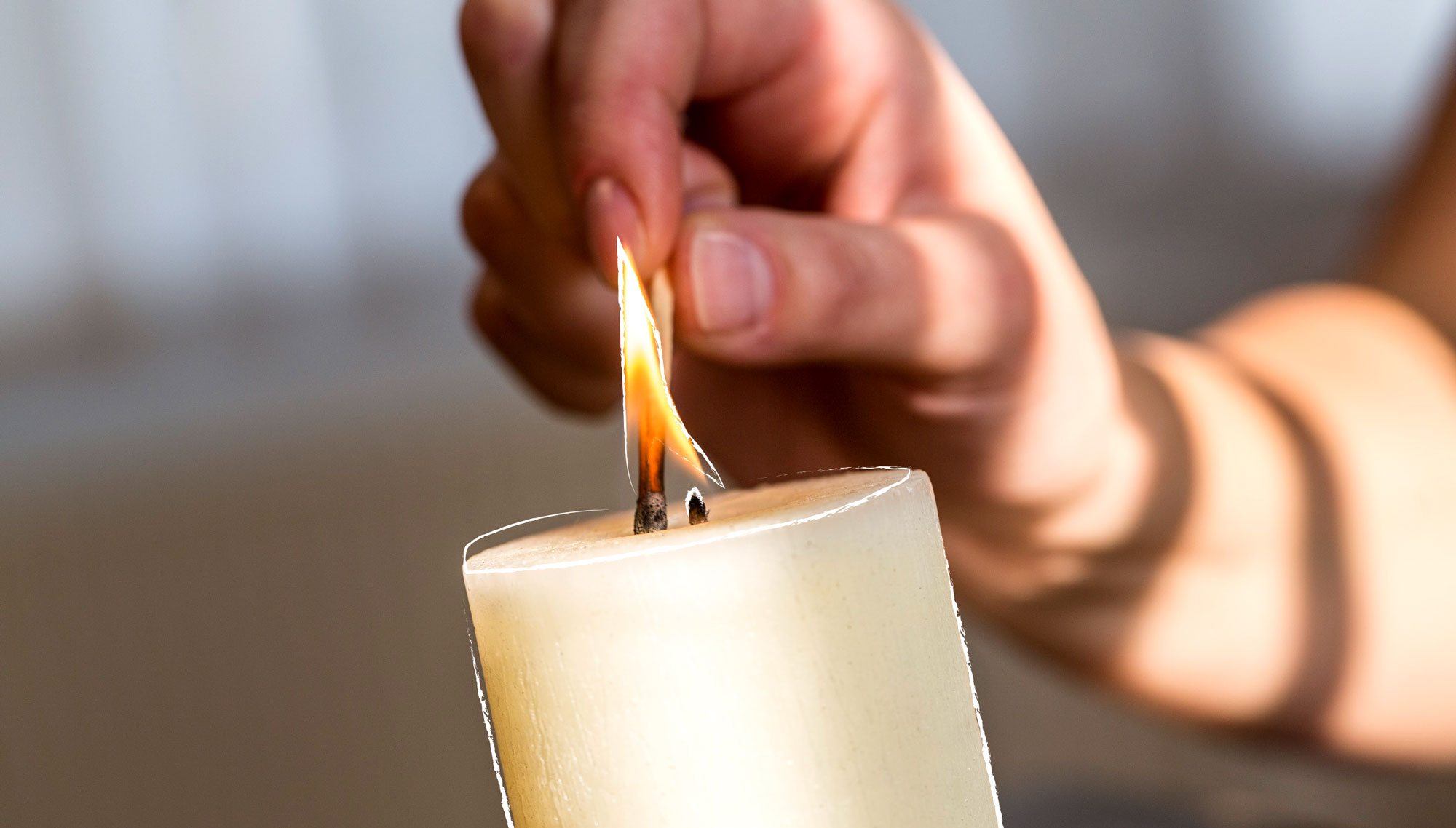 Eine Kerze wird mit einem Streichholz entzündet.